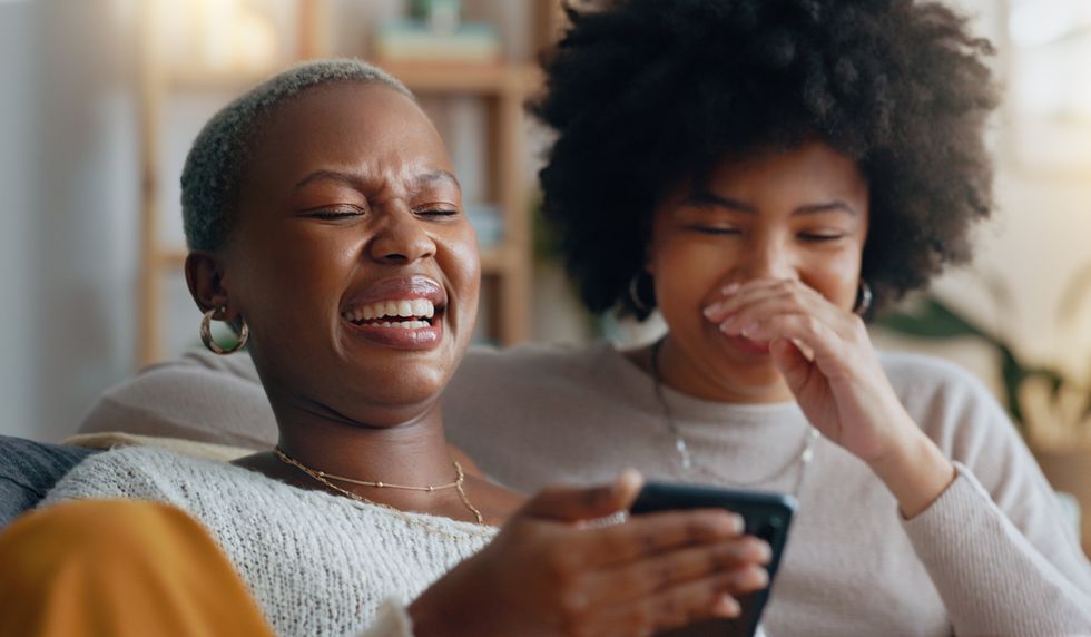 Two women looking at a cell phone and laughing