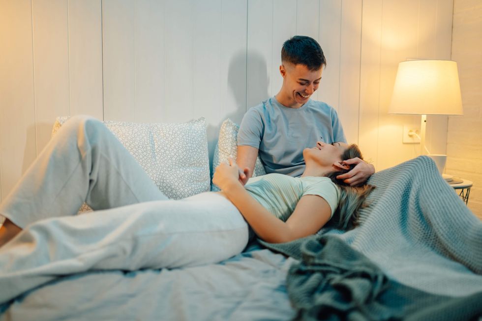 Two women lying in bed, one with her head in the other's lap.