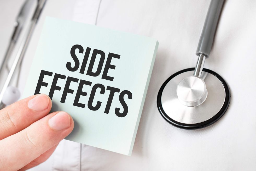 \u200bA doctor's hand holding a 'side effects' note.