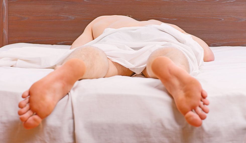 What is Podophilia? Feet of man sleeping in comfortable bed. A young man waking up in bed and stretching his arms. Man on bed