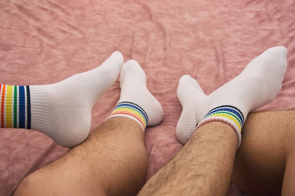 What is Podophilia? Gay couple relaxing on the bed in pajamas at home. Love and romantic relationships.