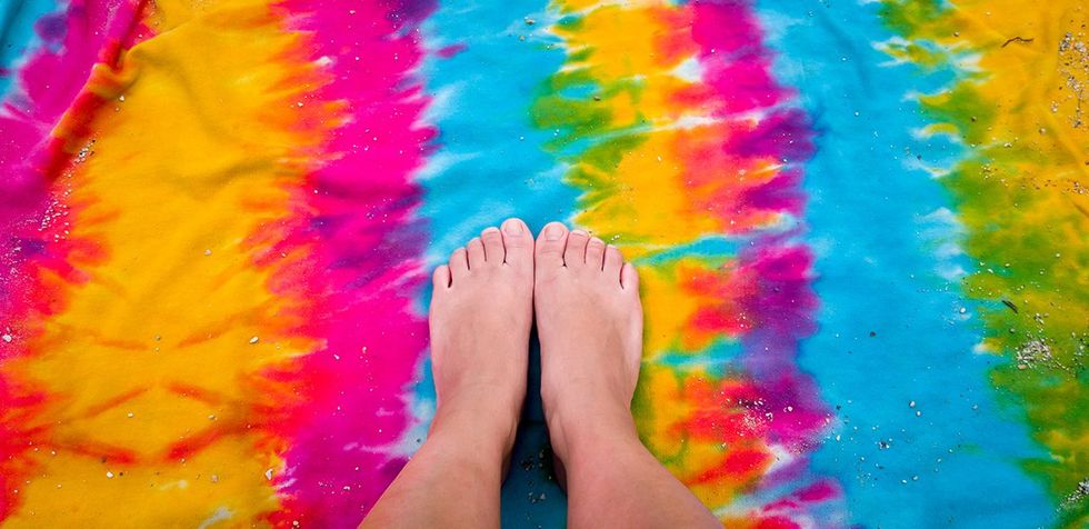 What is Podophilia? Woman feet on a hippie gay colorful towel sunbathing at the beach