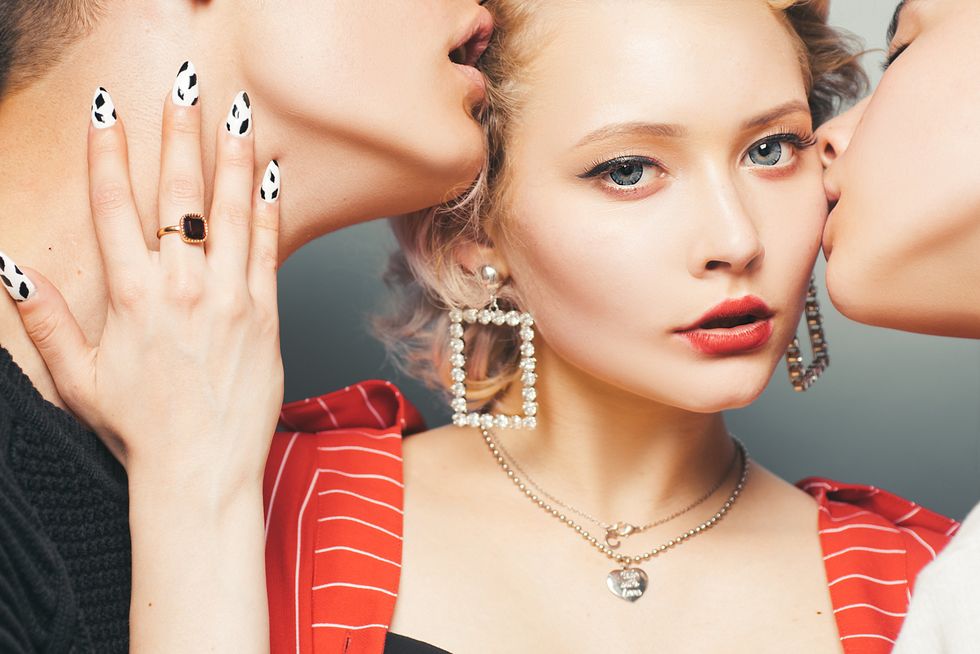 woman being kissed by two men