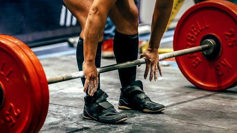 woman reaching for weights during powerlifting competition