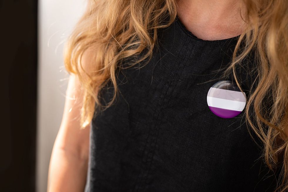 Woman with asexual badge puts on a shirt. support of minorities background.