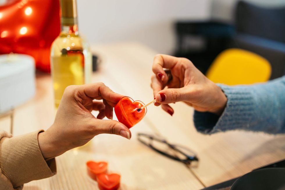 women's hands lighting a heart shaped candle