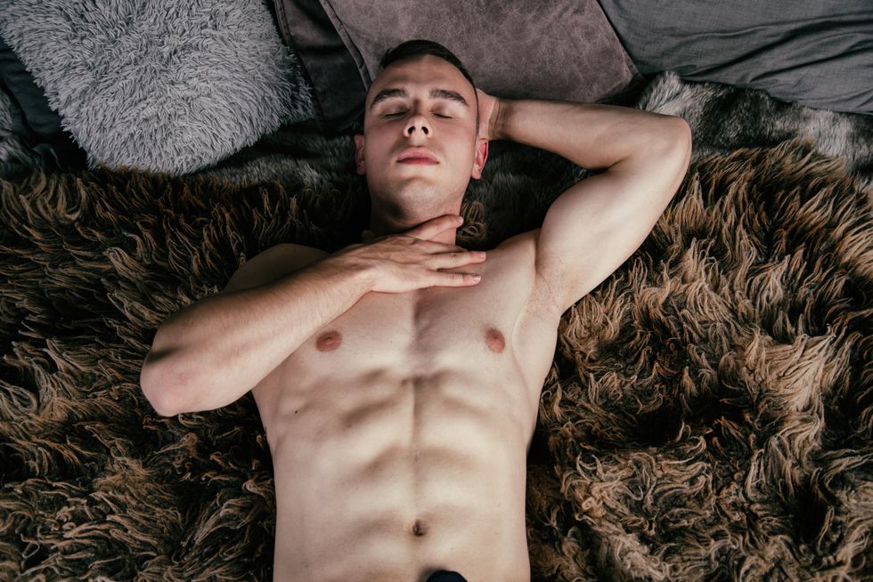Young attractive man at home relaxing on bed without a shirt. Handsome guy.