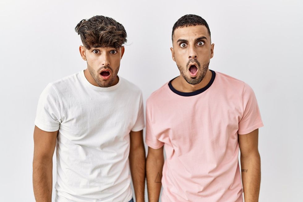 Young gay couple standing over isolated background afraid and shocked with surprise and amazed expression, fear and excited face.