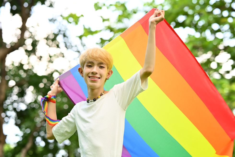 young gay person with a pride flag